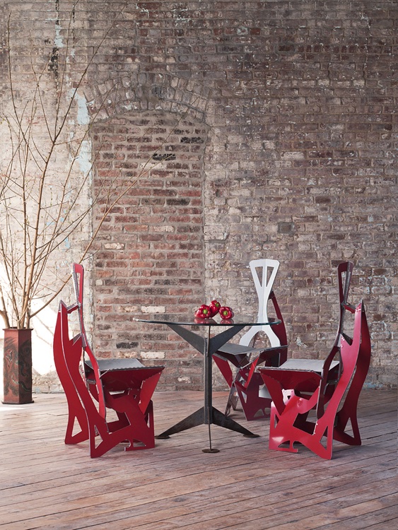Three Leaf chairs in red laminate around glass table before exposed brick wall