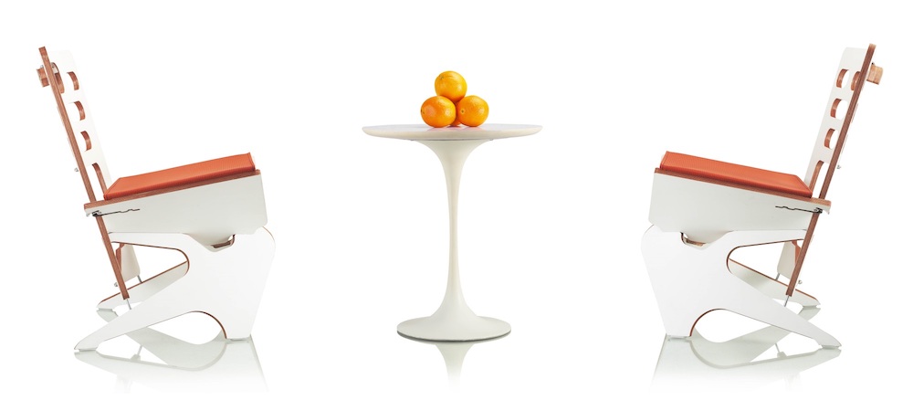 Two white Star folding chairs with orange seats next to white table with oranges